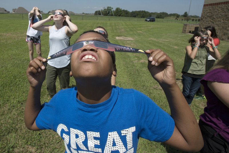 Ken Wesley, 12, watches the eclipse with his classmates Monday at Ardis Ann Middle School in Bentonville.