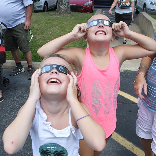 The Sentinel-Record/Richard Rasmussen WATCH PARTY: Samantha Sharper, 9, left, and her twin sister, Mallory Sharper, of Trophy Club, Texas, look up at the solar eclipse while attending a watch event at Mid-America Science Museum on Monday.