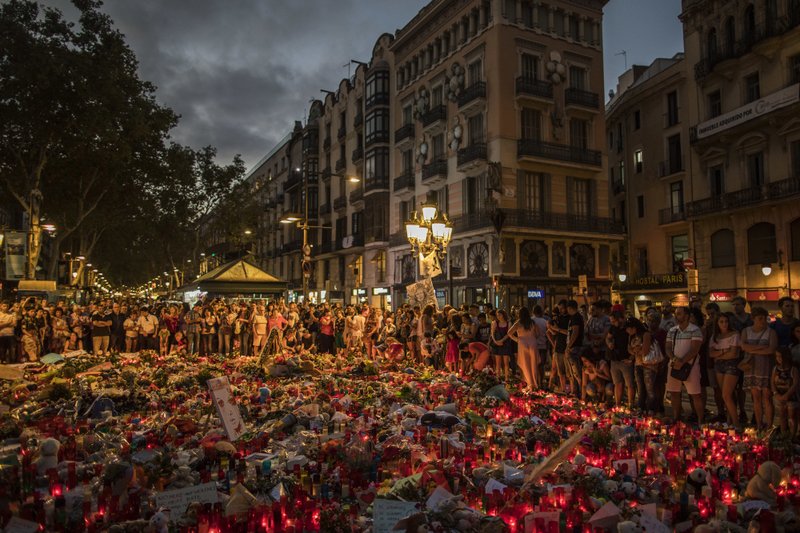 People surround memorials placed on the ground Monday after terror attacks that left 15 dead and dozens wounded last week in and around Barcelona, Spain.