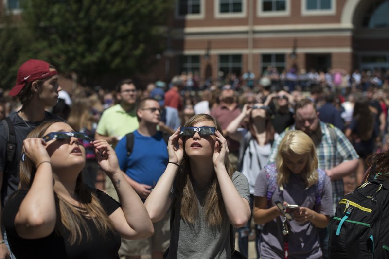 Students and faculty at Northwest Arkansas Community College stand outside the Becky Paneitz Student Center on Monday to watch the solar eclipse.