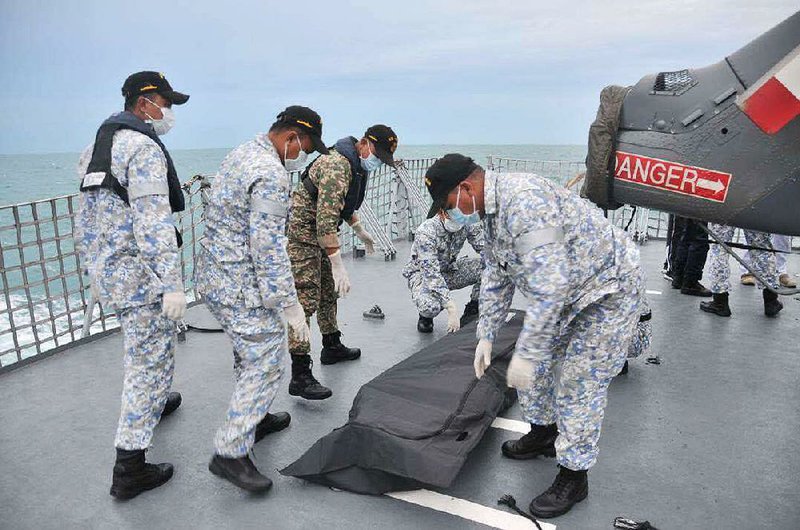 Malaysian naval personnel aboard a Malaysian frigate cover a body found Tuesday off the Johor coast during the search for missing sailors from the USS John S. McCain.