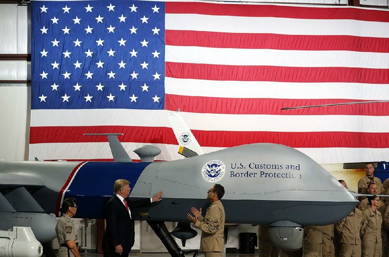 President Donald Trump pats the fuselage of a drone Tuesday during a tour of U.S. Border Patrol operations and equipment at the Marine Corps air station in Yuma, Ariz.