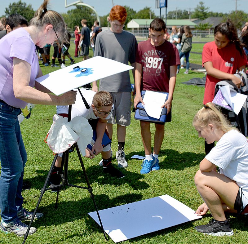 Janelle Jessen/Herald-Leader Middle school students watched as science teacher Donna Smith set up a solar viewer. The viewer consisted of a pair of binoculars on a tripod that reflected the image of the sun and moon on a piece of cardboard on the ground.