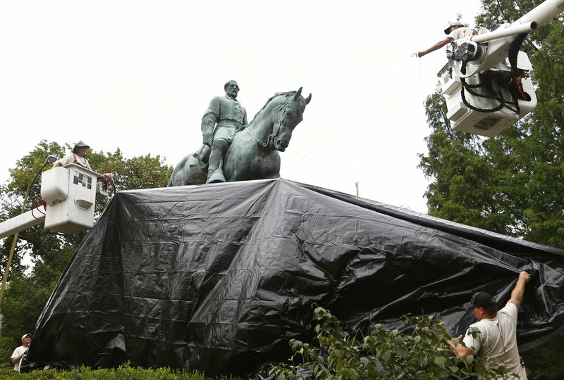City workers drape a tarp over the statue of Confederate General Robert E. Lee in Emancipation park in Charlottesville, Va., Wednesday, Aug. 23, 2017. 