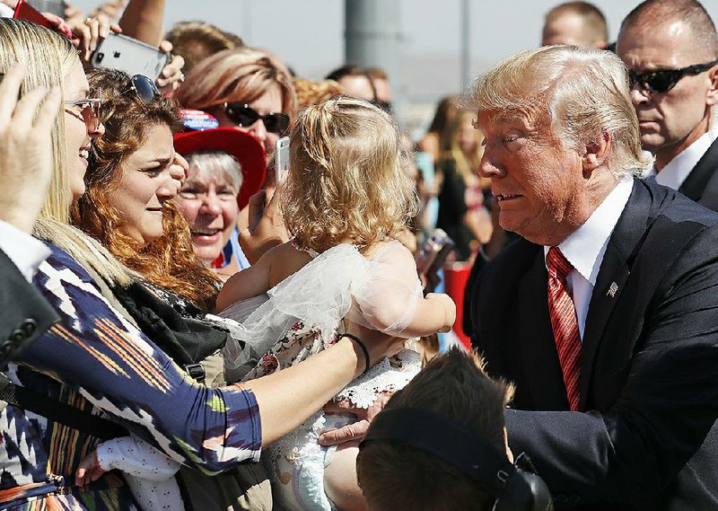 President Donald Trump moves to keep hold of a baby Wednesday while greeting supporters before his speech at an American Legion conference in Reno, Nev. 