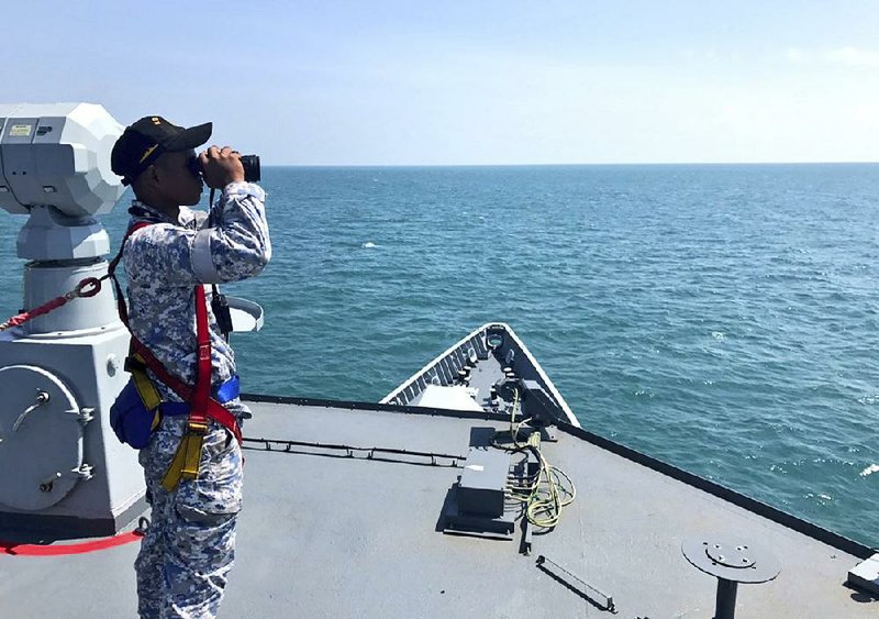 A member of the Malaysian navy scans the water off the Johor coast of Malaysia on Wednesday during a search for sailors missing from the USS John S. McCain. 
