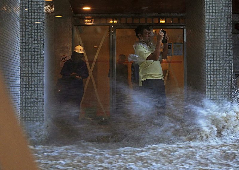 A man takes pictures as a strong wind from Typhoon Hato swirls Wednesday in Hong Kong. 