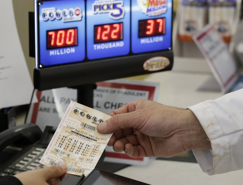 A customer is handed a Powerball ticket in Omaha, Neb., Wednesday, Aug. 23, 2017. (AP Photo/Nati Harnik)
