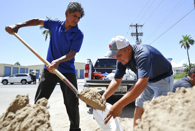Leo Sermiento, left, and Emilio Gutierrez, right, fill sandbags in preparation of a tropical system Wednesday, Aug. 23, 2017, on South Padre Island, Texas. 