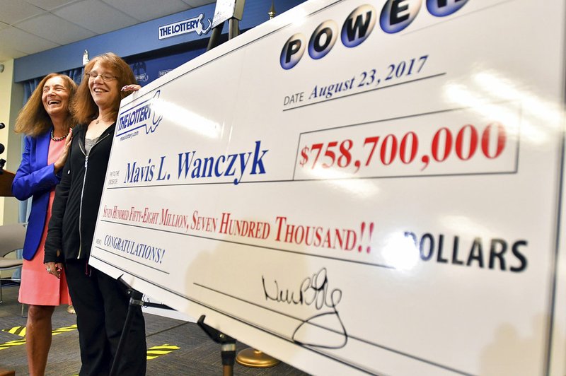 Mavis Wanczyk, of Chicopee, Mass., stands by a poster of her winnings during a news conference where she claimed the $758.7 million Powerball prize at Massachusetts State Lottery headquarters Thursday, Aug. 24, 2017, in Braintree, Mass. 