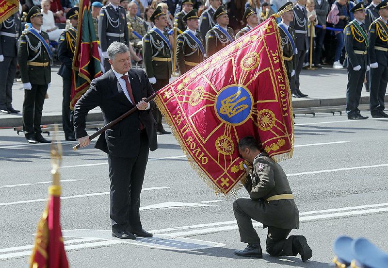 Ukrainian President Petro Poroshenko hands over the flag of a military unit to an officer who kisses it during a parade Thursday in Kiev on the 26th anniversary of Ukraine’s independence from Russia. At the parade was U.S. Defense Secretary James Mattis, who bluntly criticized Russia while affirming Ukraine’s sovereignty. 