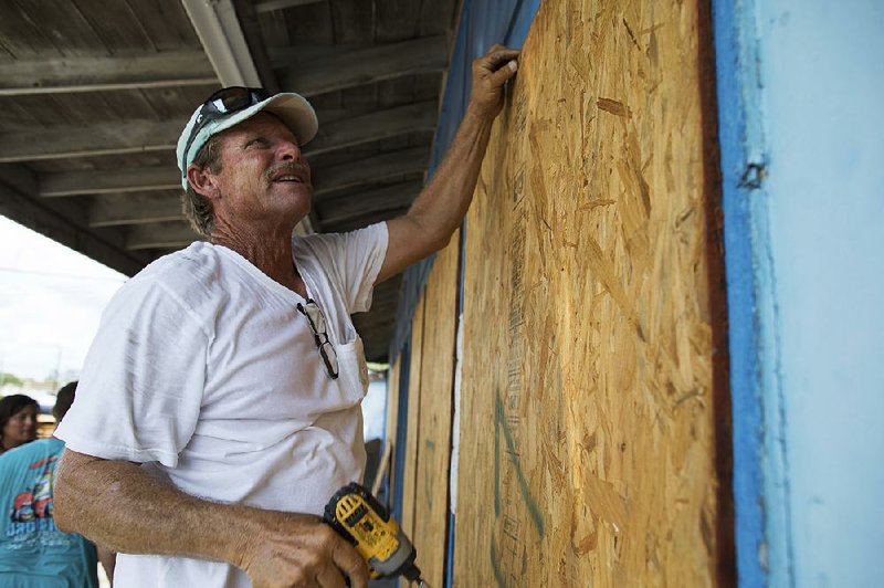Mark Jones helps board up windows Thursday at a deep-sea fishing operation in Port Aransas, Texas, ahead of Hurricane Harvey. 