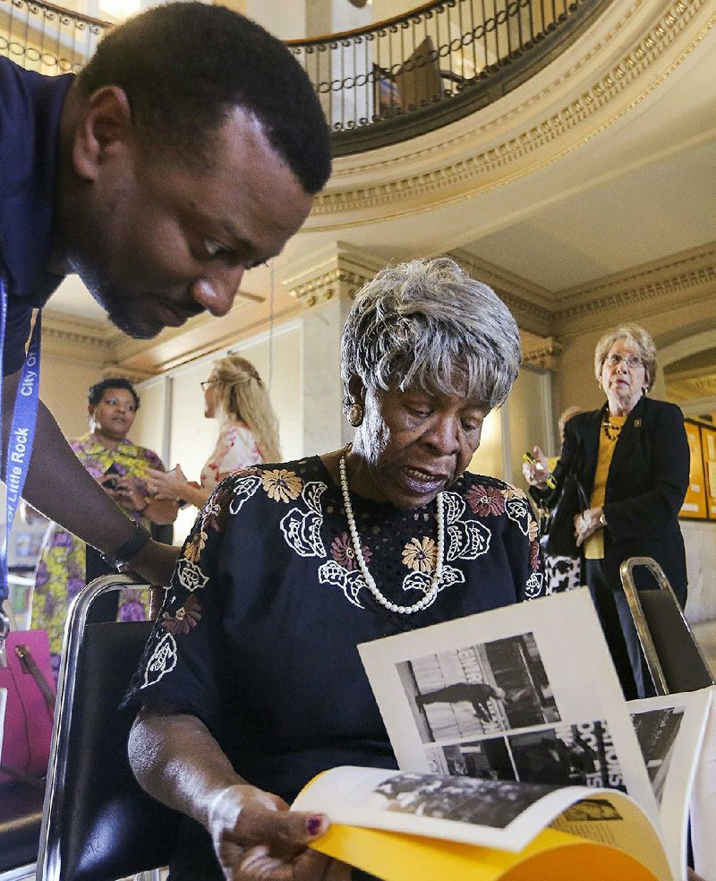 Community activist Annie Abrams (seated), who helped care for the black students who integrated Central High School in 1957, looks through a book about the integration with Kevin Howard, communication development manager for the city of Little Rock, at City Hall on Thursday. They were at an event announcing plans for an interfaith service in September during the 60th anniversary of the school’s integration. 