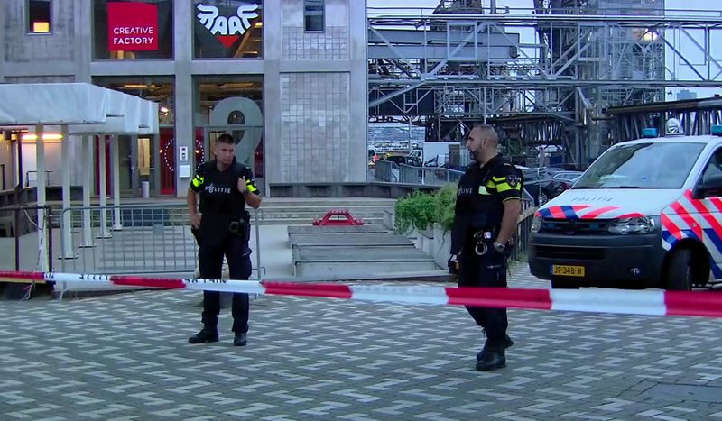 In this image taken from video officers stand behind a cordoned-off area in Rotterdam, Wednesday Aug. 23, 2017, after a concert by an American rock band was cancelled Wednesday night following a threat, the city's mayor said. Police detained the driver of a van with Spanish license plates carrying a number of gas tanks inside. (RTL via AP)