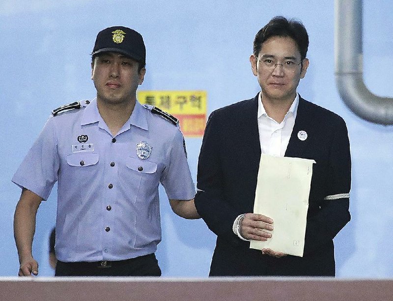 A guard leads Samsung Electronics Co. Vice Chairman Lee Jae-yong from a courtroom Friday in Seoul, South Korea, after the billionaire was sentenced to five years in prison for bribery. 