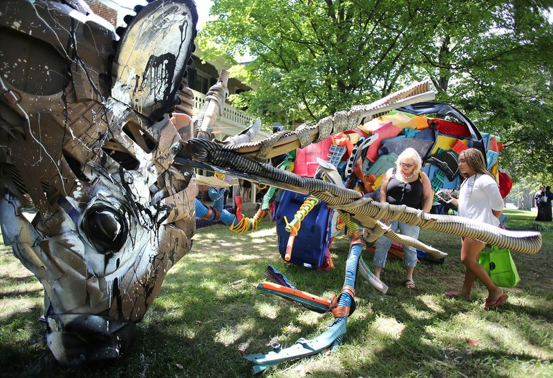 Joannie Sirlin (left) and her granddaughter Jasmine Sirlin, 11, look Friday at the three-dimensional piece by Portuguese multimedia artist Bordalo II at the Green Card Art Action celebration at the Walker-Stone House in downtown Fayetteville. Bordalo II is one of six artists working on six projects at the same time that led up to the Fayetteville Roots Festival.