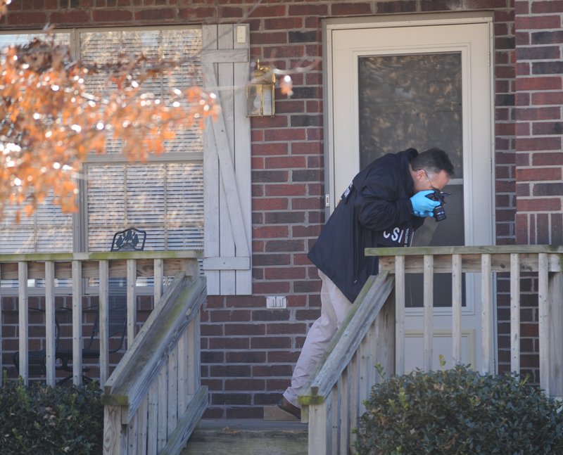 STAFF PHOTO ANDY SHUPE
John Brooks, crime scene investigator for the Fayetteville Police Department, photographs the entrance of a house at 5657 W. Reliance St. in Fayetteville Wednesday, Jan. 26, 2011, after police responded to a report of a shooting at the residence.