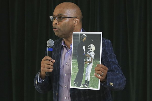 Fitz Hill, a member of the State Board of Education, holds a photo of himself coaching his son Thursday as he speaks during a press conference to announce the start of a 6th-Grade football program in the Little Rock School District and the formation of a Little Rock School District Athletic Foundation. Both the foundation and the football program will be funded by corporate and community leaders.