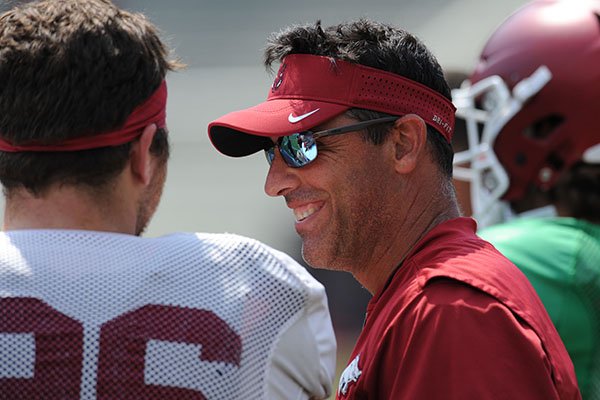 Arkansas offensive coordinator Dan Enos speaks Saturday, Aug. 5, 2017, with linebacker Karl Roesler prior to the start of a scrimmage in Razorback Stadium in Fayetteville. 