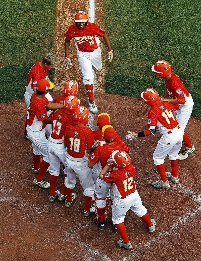 Mark Requena (top) is greeted by teammates after hitting a tworun home run off Greenville, N.C., pitcher Chase Anderson in the sixth inning, which capped off a 6-5 victory for Lufkin, Texas. Lufkin overcame a 5-0 deficit and will meet Tokyo in the championship game today.  