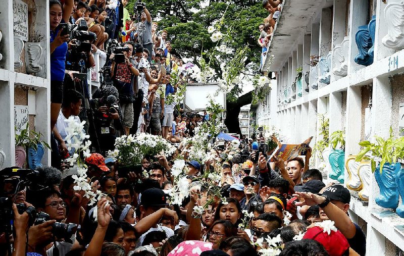 People throw white flowers Saturday at the crypt of Kian Loyd delos Santos, a 17-year-old student killed during an anti-drug crackdown in the Philippines