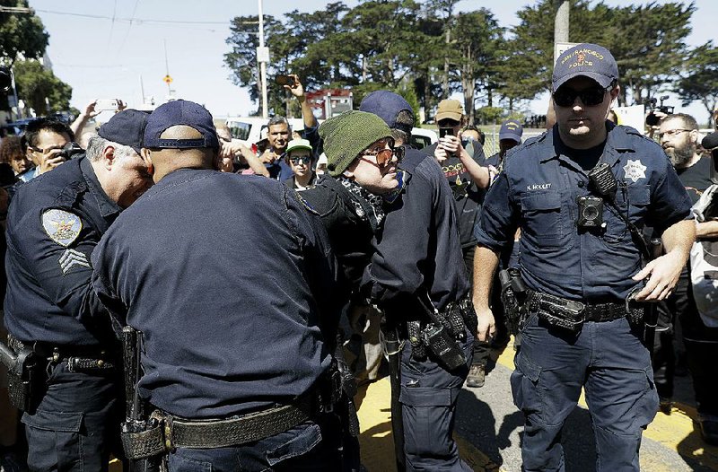 San Francisco police officers arrest a protester Saturday near Alamo Square. About 1,000 people showed up to counterprotest a “freedom rally” that ended up not taking place.