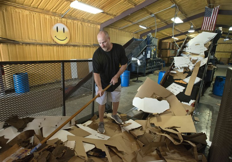 Jackson Taylor of Rogers helps unload cardboard from a trailer into a shredder/compactor Aug. 17 at the Bella Vista Recycling Center.