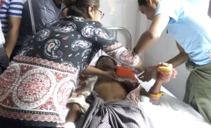 In this image made from video, a man lying on a bed with a bandaged hand is cared for in a hospital in Buthidaung township, Myanmar, Friday, Aug. 25, 2017. 