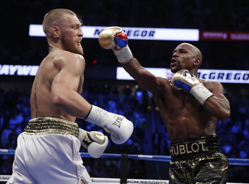 Floyd Mayweather Jr. hits Conor McGregor in a super welterweight boxing match Saturday, Aug. 26, 2017, in Las Vegas. (AP Photo/Isaac Brekken)