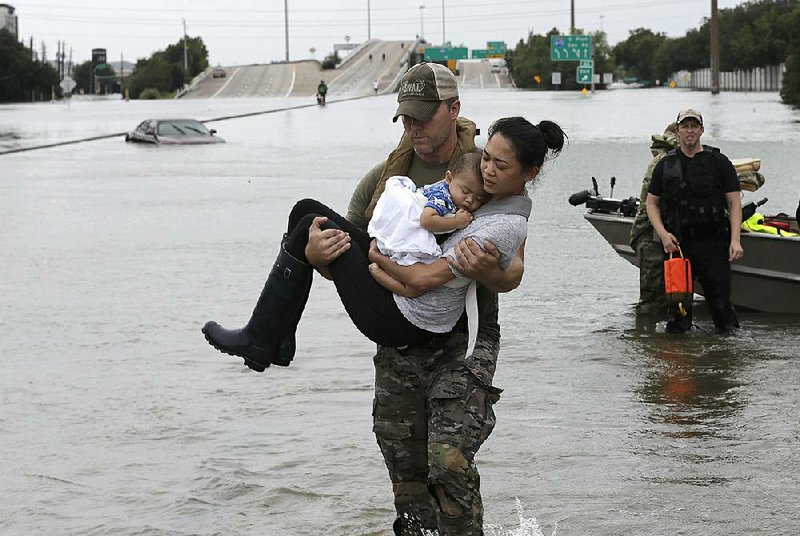 Houston police SWAT officer Daryl Hudeck carries Catherine Pham and her 13-month-old son Aiden after rescuing them from their home surrounded by fl oodwaters from Tropical Storm Harvey on Sunday in Houston.