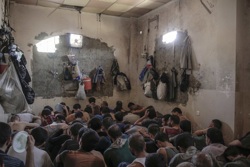 In this Tuesday, July 18, 2017 file photo, suspected Islamic State members sit inside a small room in a prison south of Mosul.