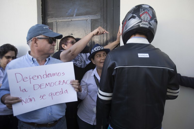 Demonstrators against President Jimmy Morales block the way to a man, who identified himself as messenger of the Foreign Ministry, at the main entrance of the the United Nations International Commission Against Impunity in Guatemala City, Sunday, Aug. 27, 2017. Guatemalan President Jimmy Morales announced Sunday he is expelling of Ivan Velasquez, the head of a U.N. anti-corruption commission that is investigating the president's campaign financing. (AP Photo/Moises Castillo)