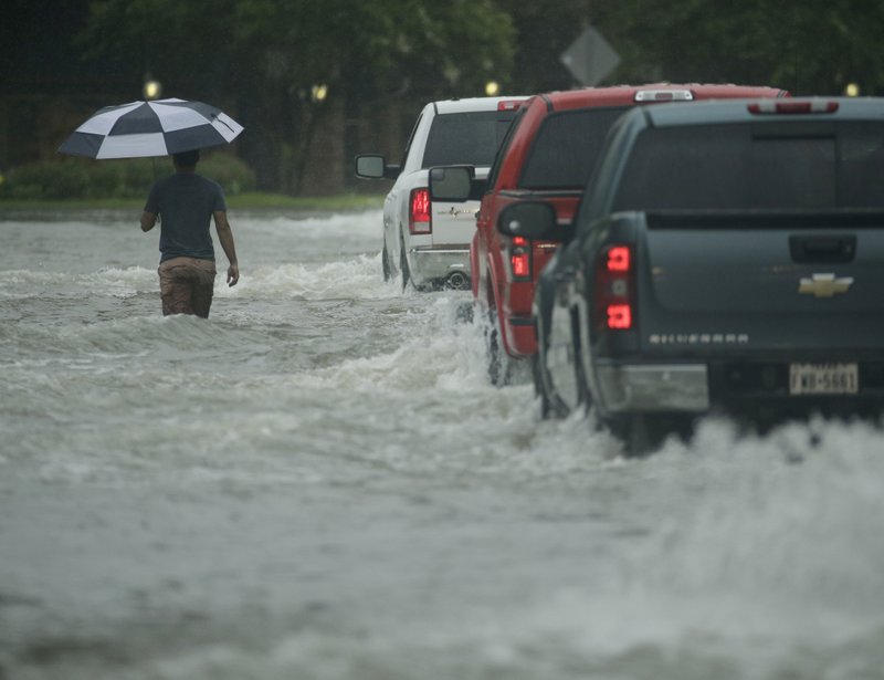 A pedestrian crosses a street inundated by floodwaters from Tropical Storm Harvey on Sunday, Aug. 27, 2017, in Houston, Texas. 