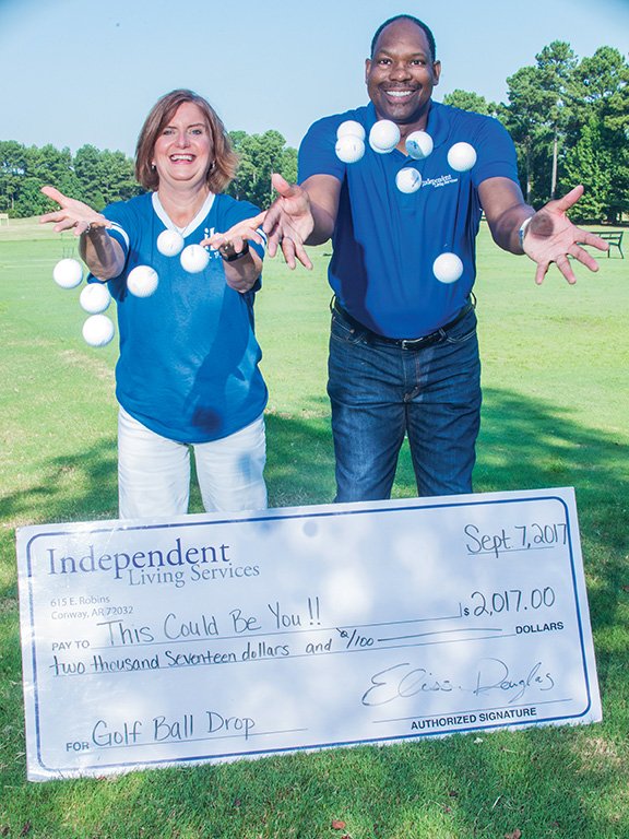 Elissa Douglas, executive director of Independent Living Services in Conway, and Robert Wright, director of development and supportive employment for the nonprofit organization, throw golf balls into the air at Centennial Valley Country Club in Conway. The 12th annual ILS Golf Ball Drop is scheduled from 5:30-7 p.m. Sept. 7. The person whose golf ball is closest to hole will win $2,017. Tickets for numbered golf balls, which will be dropped from a Conway Fire Department bucket truck, can be purchased online at www.indliving.org, at the nonprofit agency at 615 E. Robins St. or at the event.