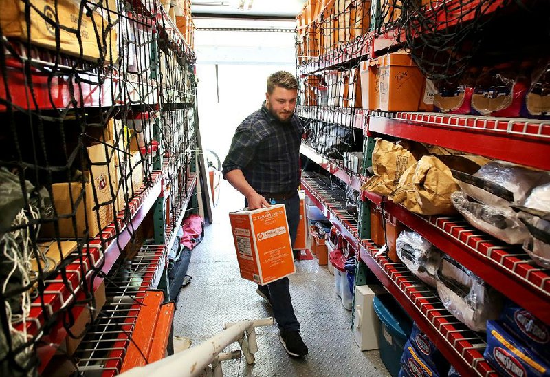 Clay Kleinebreil, an intern in internal communications at Tyson Foods, loads frying oil Monday onto a Meals that Matter Tyson Food Disaster tractor trailer in Springdale. Kleinebreil and Pat Bourke, manager of Corporate Social Responsibility, loaded the last remaining items on the trailer and portable kitchen that will deploy Wednesday morning to provide relief after Tropical Storm Harvey.