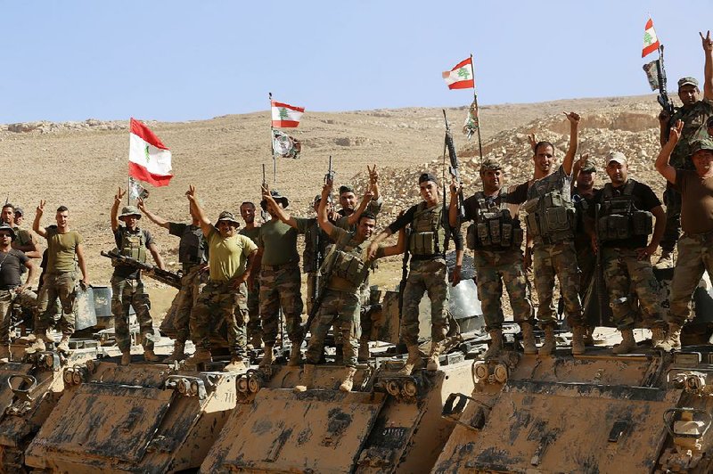 Lebanese army soldiers flash victory signs as they pause atop an armored personnel carrier during a media trip organized by the Lebanese army Monday on the outskirts of Ras Baalbek in northeast Lebanon.