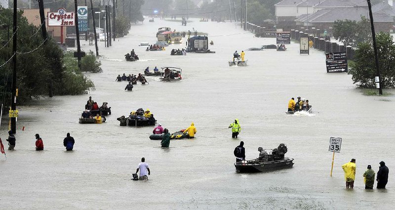 Water continues to rise Monday in Houston as rescue boats fill a flooded street to pick up people stranded by Harvey.