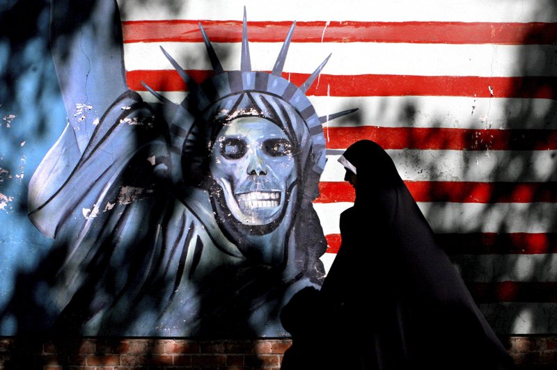 In this Sept. 25, 2007 file photo, an Iranian woman walks past graffiti art characterizing the U.S. Statue of Liberty, painted on the wall of the former U.S. Embassy in Tehran, Iran. 