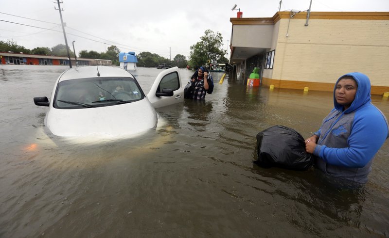 Conception Casa, center, and his friend Jose Martinez, right, check on Rhonda Worthington after her car became stuck in rising floodwaters from Tropical Storm Harvey in Houston, Texas, Monday, Aug. 28, 2017. The two men were evacuating their home that had become flooded when they encountered Worthington's car floating off the road. (AP Photo/LM Otero)
