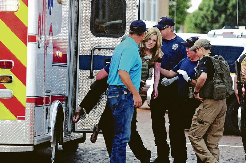 An injured woman is helped into an ambulance Monday in Clovis, N.M., after a shooting inside a public library that left two workers dead and four people wounded. 