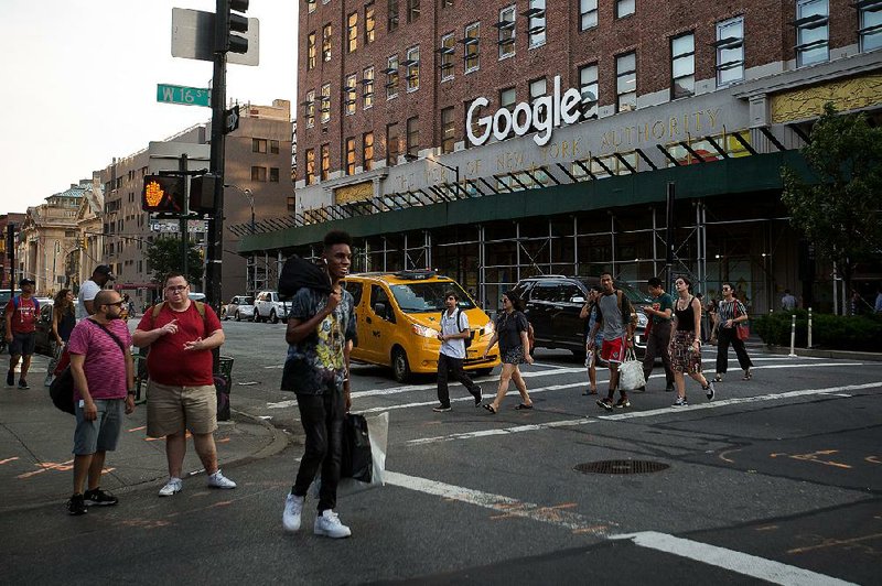 Pedestrians pass the Google Inc. offices in New York in August 2016. Google’s parent company, Alphabet Inc., has agreed to comply with European Union demands to change the way it runs its shopping search service. 