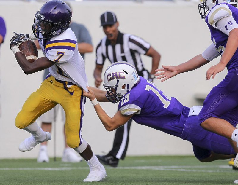 Mayflower running back TayShun Mattison (left) tries to avoid being dragged down by CAC’s Garrett Overstreet during the Eagles’ 50-15 victory over the Mustangs on Tuesday at War Memorial Stadium in Little Rock. 
