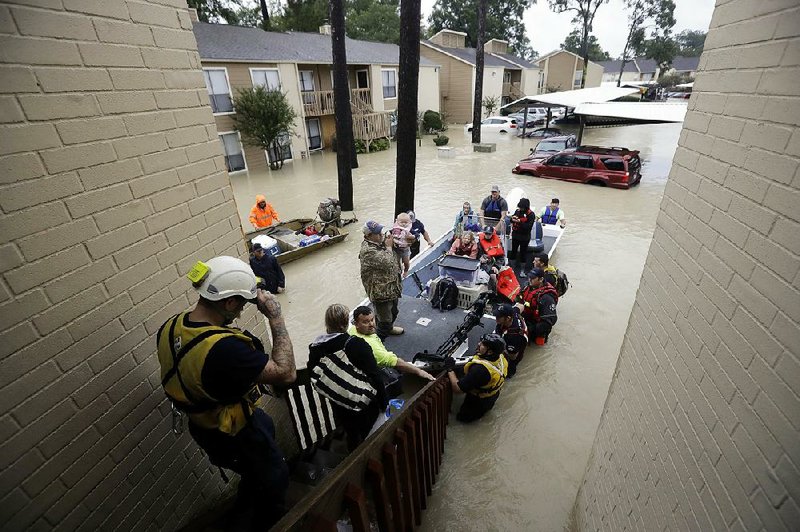 Rescuers help the Reznor family and others get out of their flooded homes Tuesday at an apartment complex in Kingwood, Texas, northeast of Houston. 
