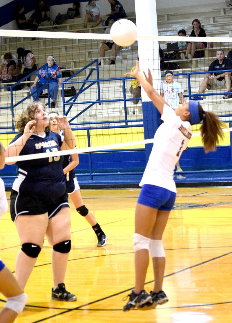 Photo by Mike Eckels Desi Meek (Decatur 1) returns a ball as a Lady Spartan player gets ready to block during the Aug. 22 Decatur-Northwest Arkansas Classical Academy senior girls&#8217; volleyball match at Peterson Gym in Decatur.