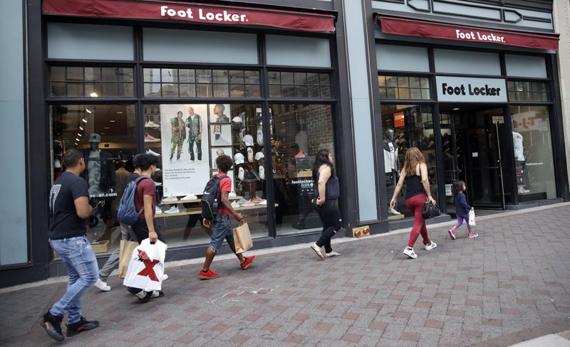 In this Friday, Aug. 25, 2017, photo, shoppers walk past a Foot Locker store in Boston. On Tuesday, Aug. 29, 2017, the Conference Board releases its July index on U.S. consumer confidence. (AP Photo/Charles Krupa)