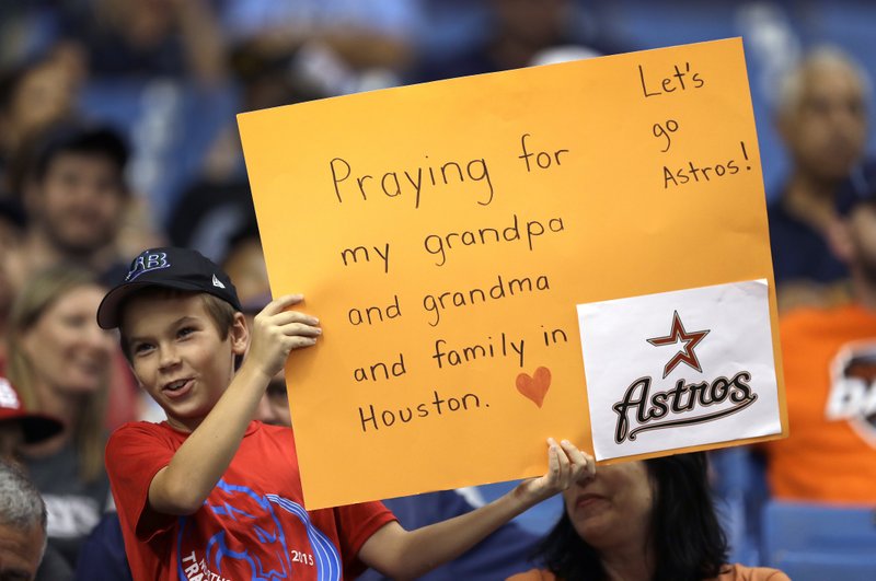 A young fan holds up a sign during the first inning of a baseball game between the Houston Astros and the Texas Rangers Tuesday, Aug. 29, 2017, in St. Petersburg, Fla. The Astros moved their three-game home series against the Rangers to St. Petersburg because of unsafe conditions from Hurricane Harvey. (AP Photo/Chris O'Meara)