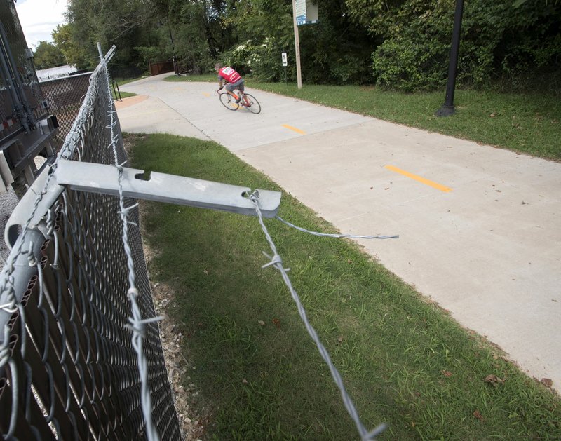 A cyclist rides on the Razorback Greenway Trail near the intersection with the Tsa-La-Gi Trail in south Fayetteville Tuesday August 29, 2017. A nearby barbed wire fence was used to set a trap on the trail sending one man to the hospital on Aug. 25. 