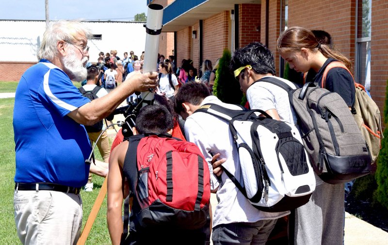 Mike Eckels (left) steadied his telescope while students captured a rare glimpse of a 90 percent solar eclipse near the front entrance at Decatur High School in Decatur Aug.21