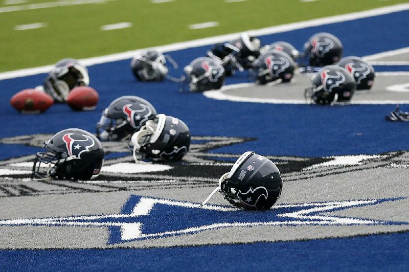 Several Houston Texans helmets sit over the Dallas Cowboys logo in the end zone as the Texans prepared for a morning workout Monday at the Cowboys training facility in Frisco, Texas. The Texans were working out at the practice facility of the Cowboys because of !ooding in Houston. An exhibition game scheduled for tonight in Houston was canceled Wednesday. 