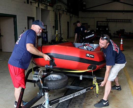 The Sentinel-Record/Richard Rasmussen LOADING UP: Hot Springs Fire Department Lt. Kenny Talbert, left, and driver Ricky Ilenfeld, both members of the department's swift water rescue team, load their 15-foot Zodiac rescue boat as they prepare to leave for Texas Wednesday morning. A four-man crew is deploying to the storm ravaged, flooded area to help in the wake of Hurricane Harvey.